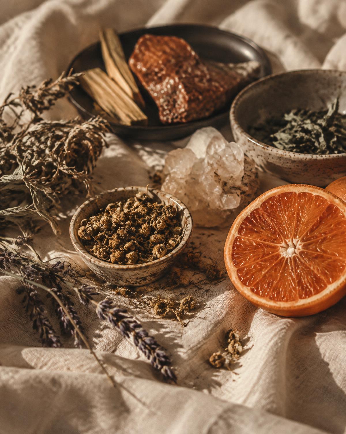 Dried herbs, mineral stones and a halved orange arranged on warm linen